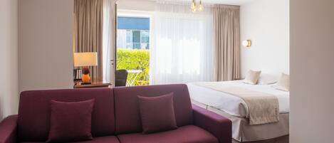 Une chambre d’hôtel avec un lit, un canapé, une table basse et une vue sur l’extérieur.