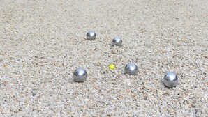 A gravel path with several metallic balls, leading to a building with a tower and a covered area with chairs. - Château de Sancy (Sancy)