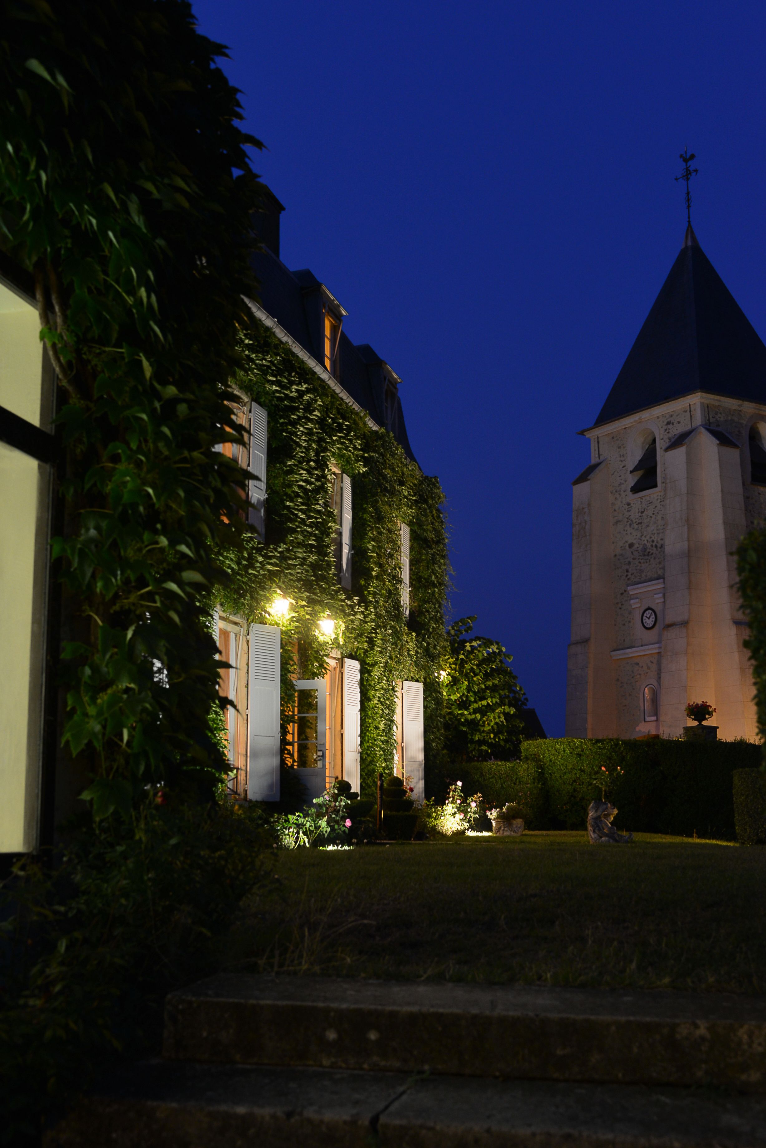 A historic building with a clock tower, ivy-covered walls, and a well-lit entrance.