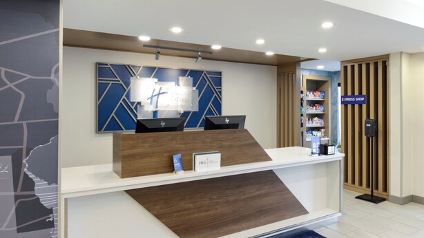 Bancada de recepção com design moderno, esquema de cores azul e branco, e placa para a loja express.