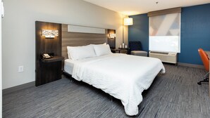 Quarto de hotel moderno com uma cama grande, mesas de cabeceira, uma escrivaninha, uma cadeira e uma janela com persianas.
