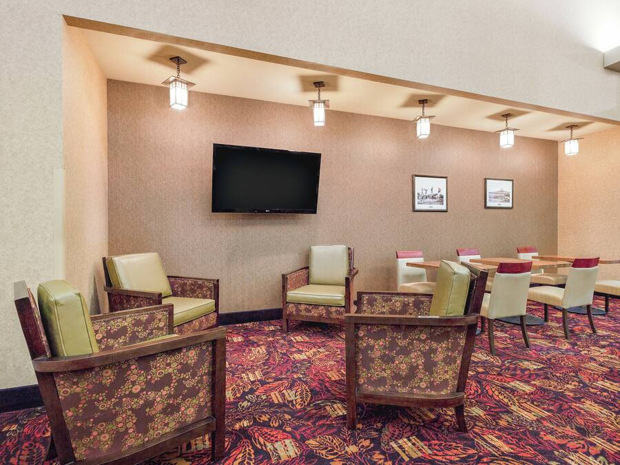 A conference room with a flat-screen TV mounted on the wall, surrounded by chairs and tables.