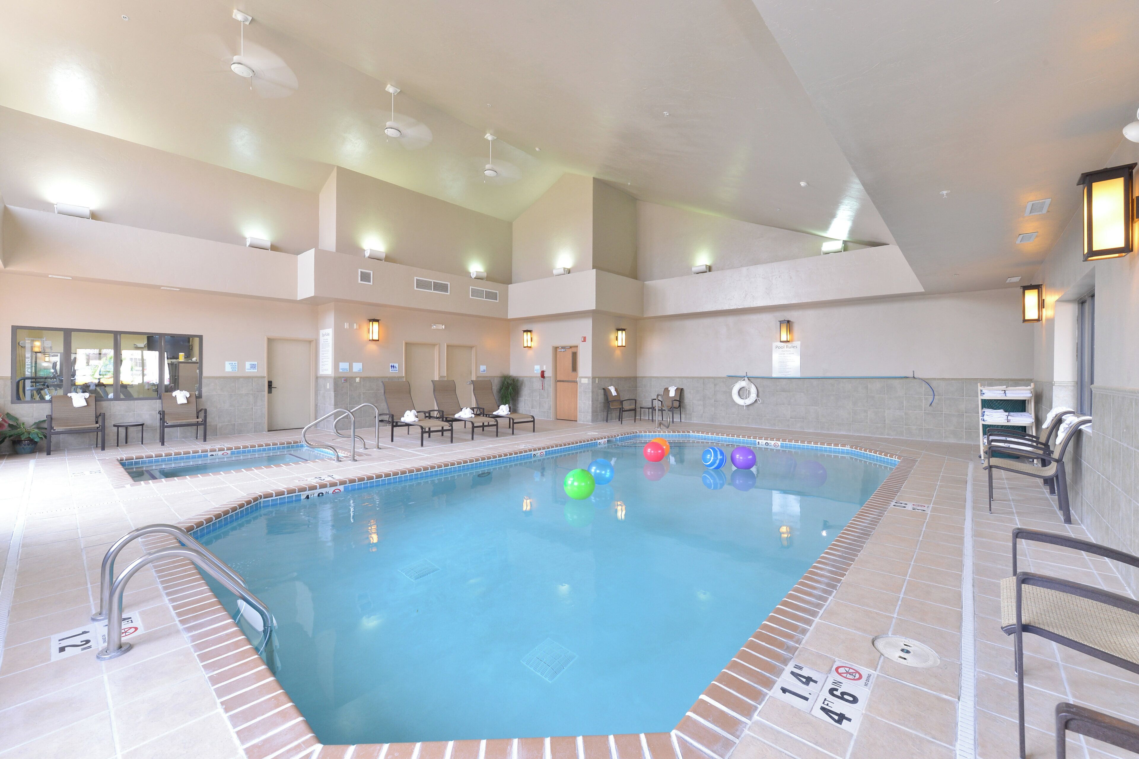 Une piscine intérieure dotée de plusieurs couloirs de nage, de chaises longues et d’un espace aménagé au bord du bassin, avec un poste de surveillance pour les sauveteurs.