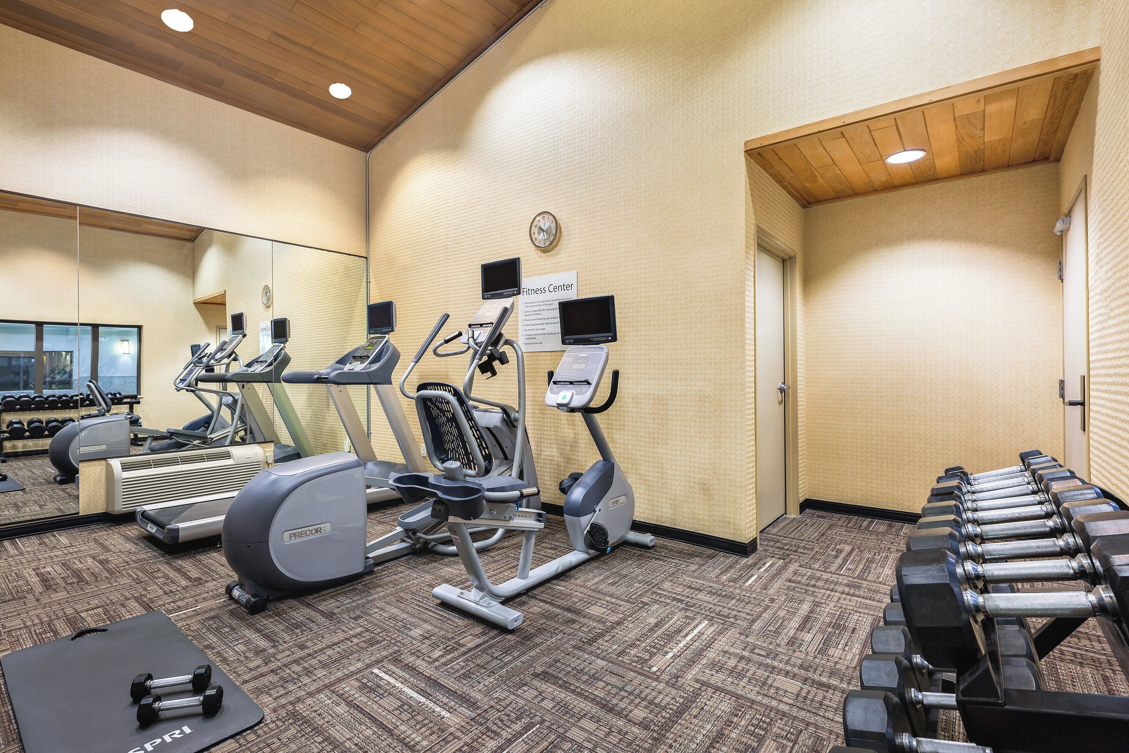 A fitness center with treadmills, an elliptical, and dumbbells.