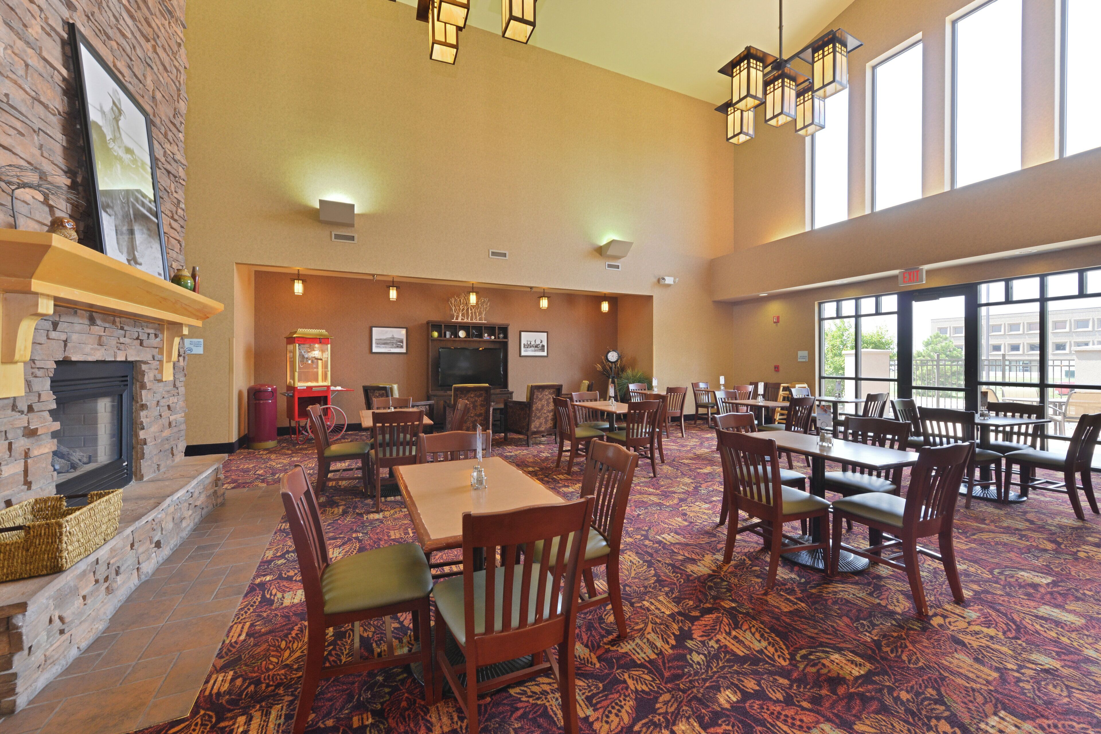 A hotel dining area with brick walls, a fireplace, and a large window providing a view of the outside.