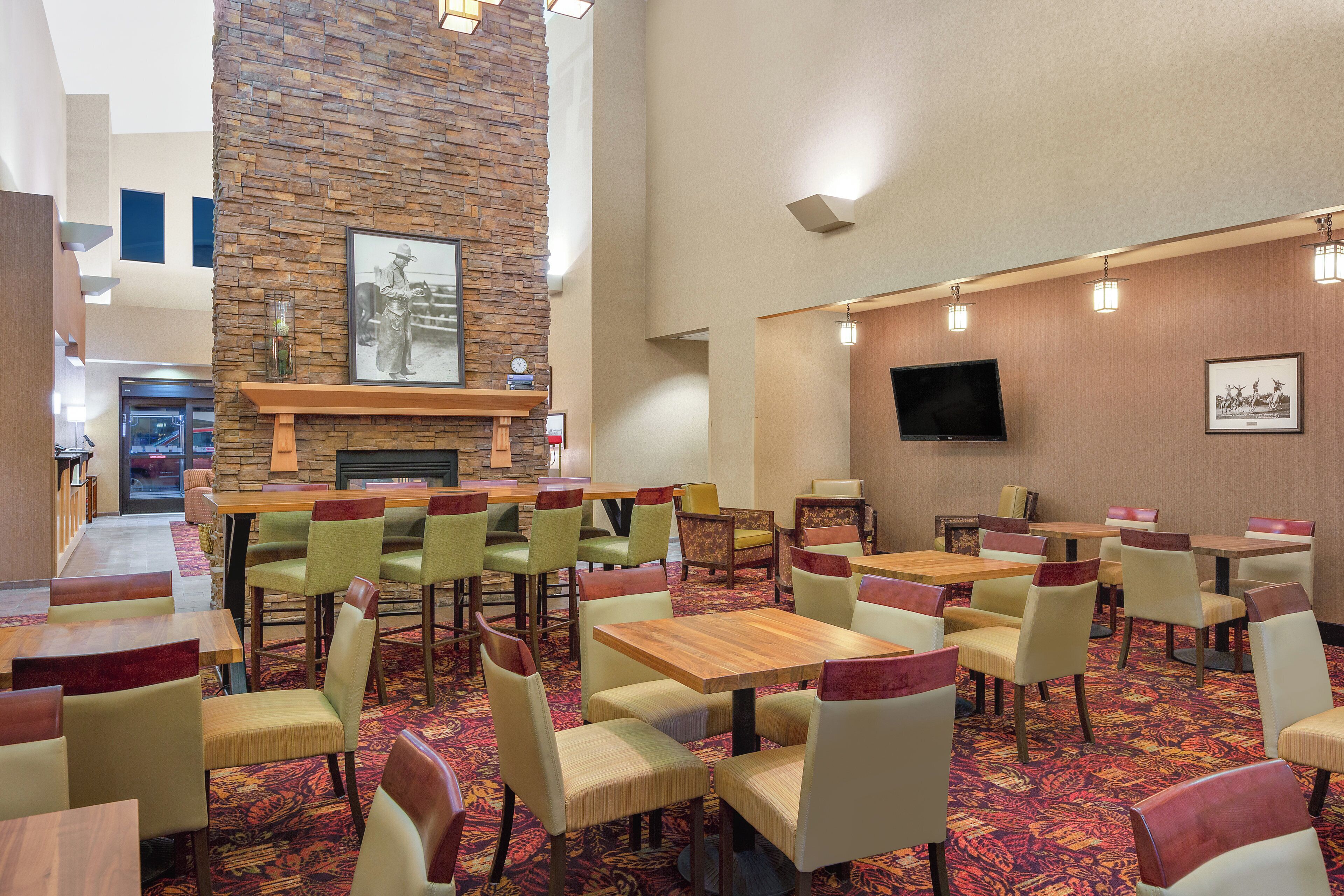 A hotel lobby with a stone wall, a fireplace, a television, and multiple seating areas.