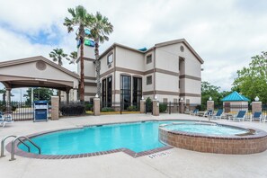 A hotel with a swimming pool, a covered area, and a sign for a nearby Express location. - Holiday Inn Express Hotel & Suites Lake Charles by IHG (Lake Charles)