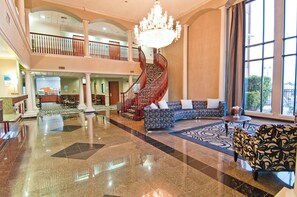 A spacious lobby with a grand staircase, a chandelier, and a seating area with a patterned rug. - Holiday Inn Express Hotel & Suites Lake Charles by IHG (Lake Charles)
