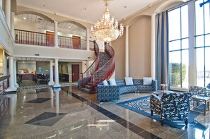 A spacious lobby with a grand chandelier, a staircase, and a seating area with patterned sofas. - Holiday Inn Express Hotel & Suites Lake Charles by IHG (Lake Charles)