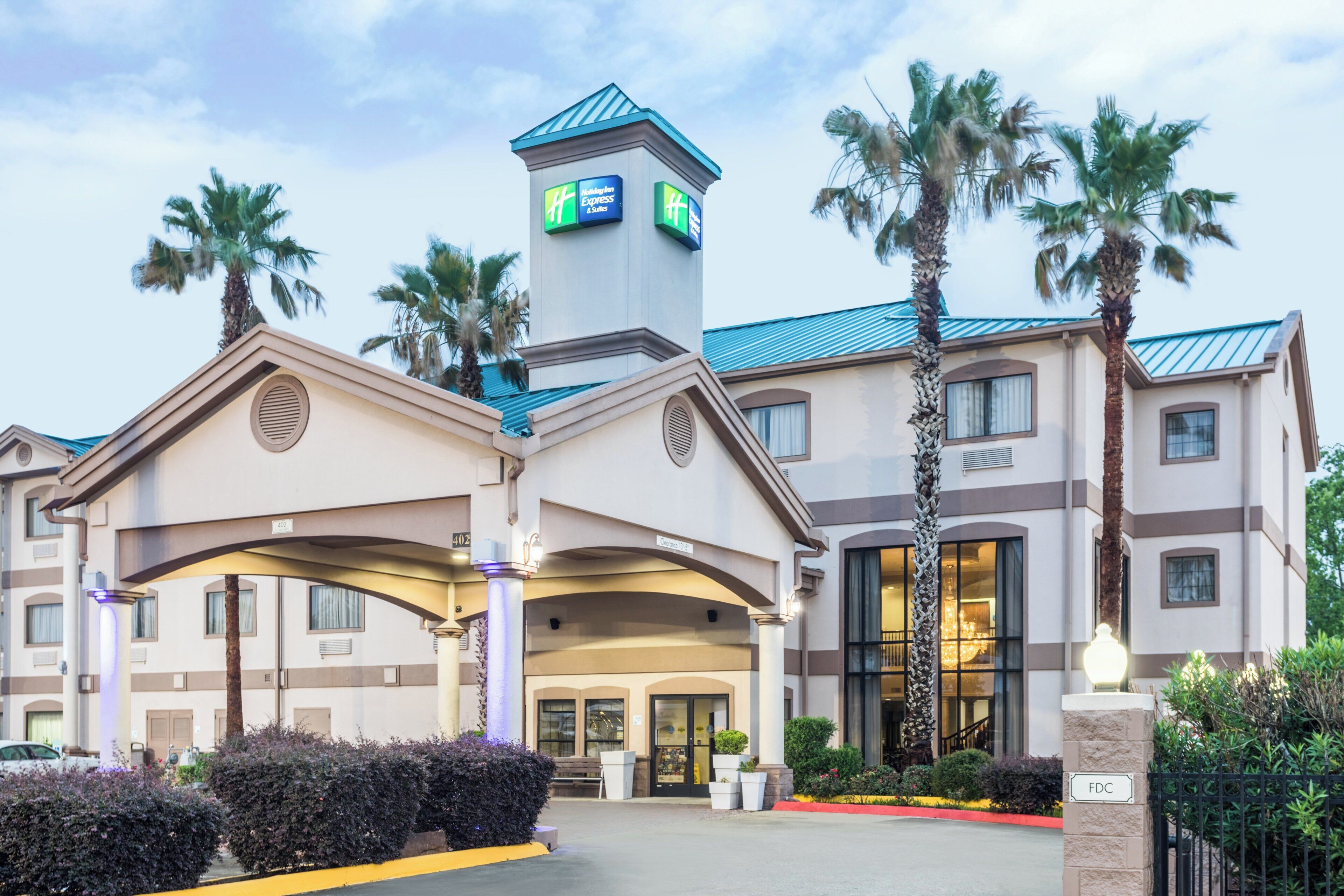 Un hotel con una torre destacada, palmeras y un cielo despejado.