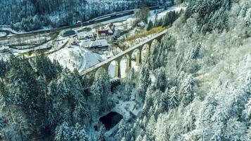 Eine schneebedeckte Brücke mit Gebäuden an beiden Seiten, umgeben von dichtem Wald.