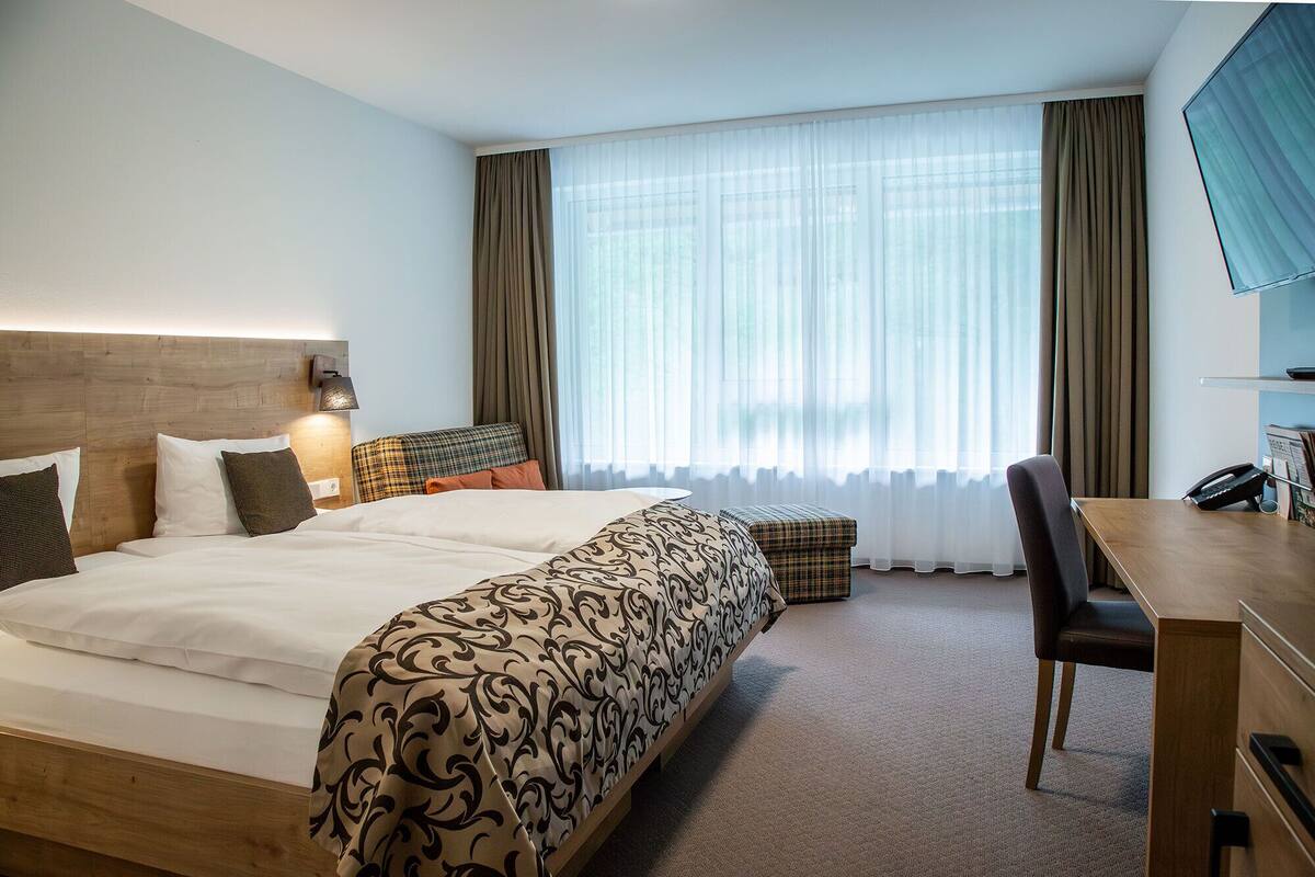 Ein Hotelzimmer mit einem großen Bett, einem Schreibtisch, einem Sessel und einem Telefon.