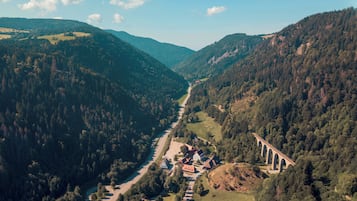 An aerial view of a valley with a bridge, a road, and a cluster of buildings.