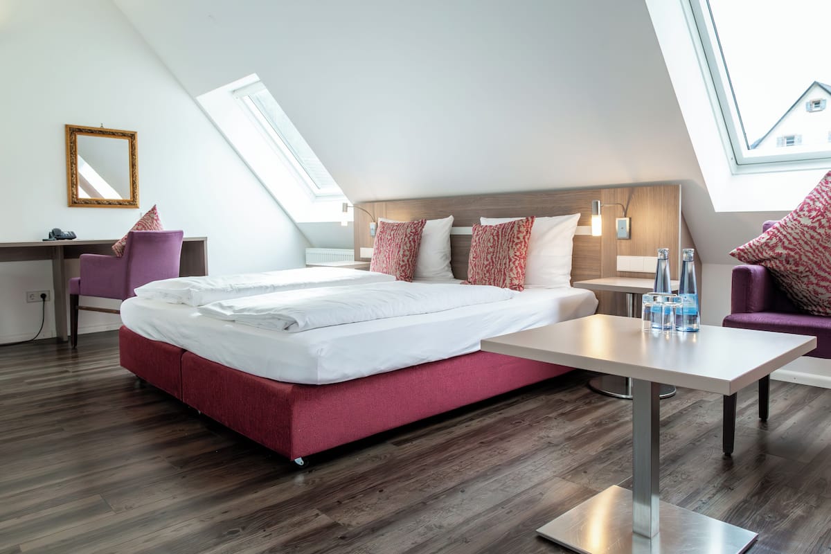 Ein modernes Hotelzimmer mit einem großen Bett, einem Schreibtisch und einem Oberlicht.