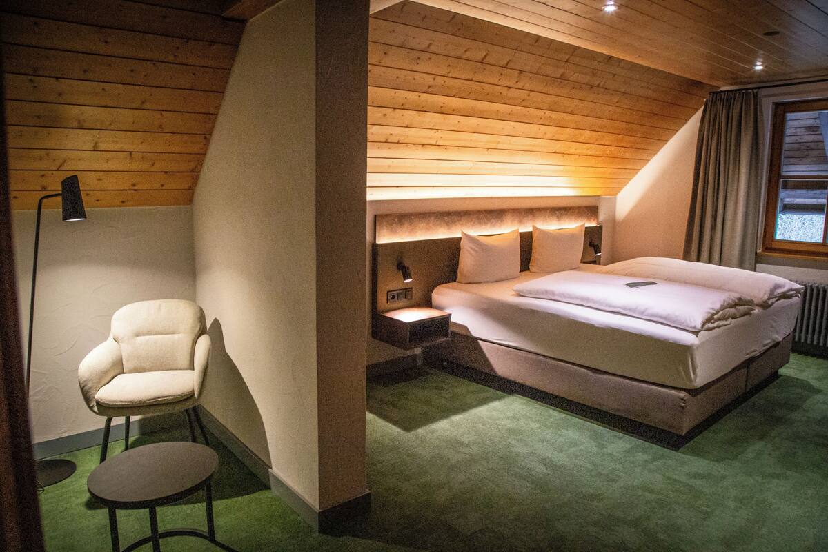 Ein Schlafzimmer mit einem Bett, einem Sessel, einem Nachttisch und einer Lampe.
