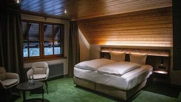 Un dormitorio con una cama grande, una silla, una mesita y una ventana con cortinas.