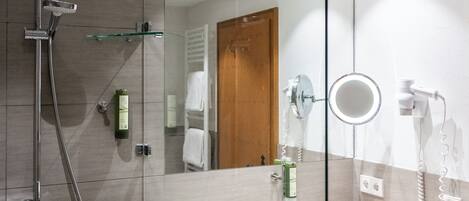 A modern bathroom with a glass shower enclosure, a sink with a mirror, and a hairdryer.
