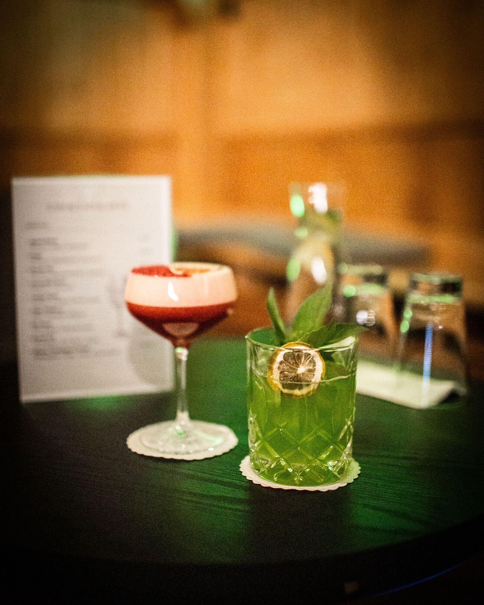 Two drinks on a table with a menu in the background.