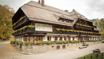 A traditional wooden building with balconies, stone walls, and a sign indicating a restaurant.