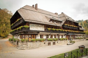 A traditional wooden building with balconies, stone walls, and a sign indicating a restaurant. - Hotel Hofgut Sternen | Ravennaschlucht (Breitnau)