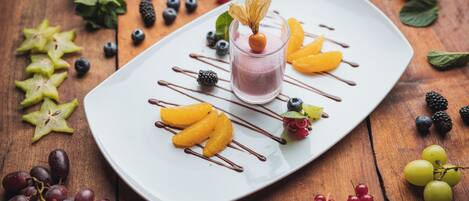 A dessert plate with a glass of pink drink, surrounded by various fruits and berries.