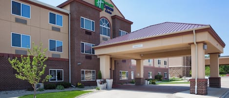 A Holiday Inn Express hotel with a covered entrance, brick facade, and a clear sky.