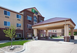 A Holiday Inn Express hotel with a covered entrance, brick facade, and a clear sky.