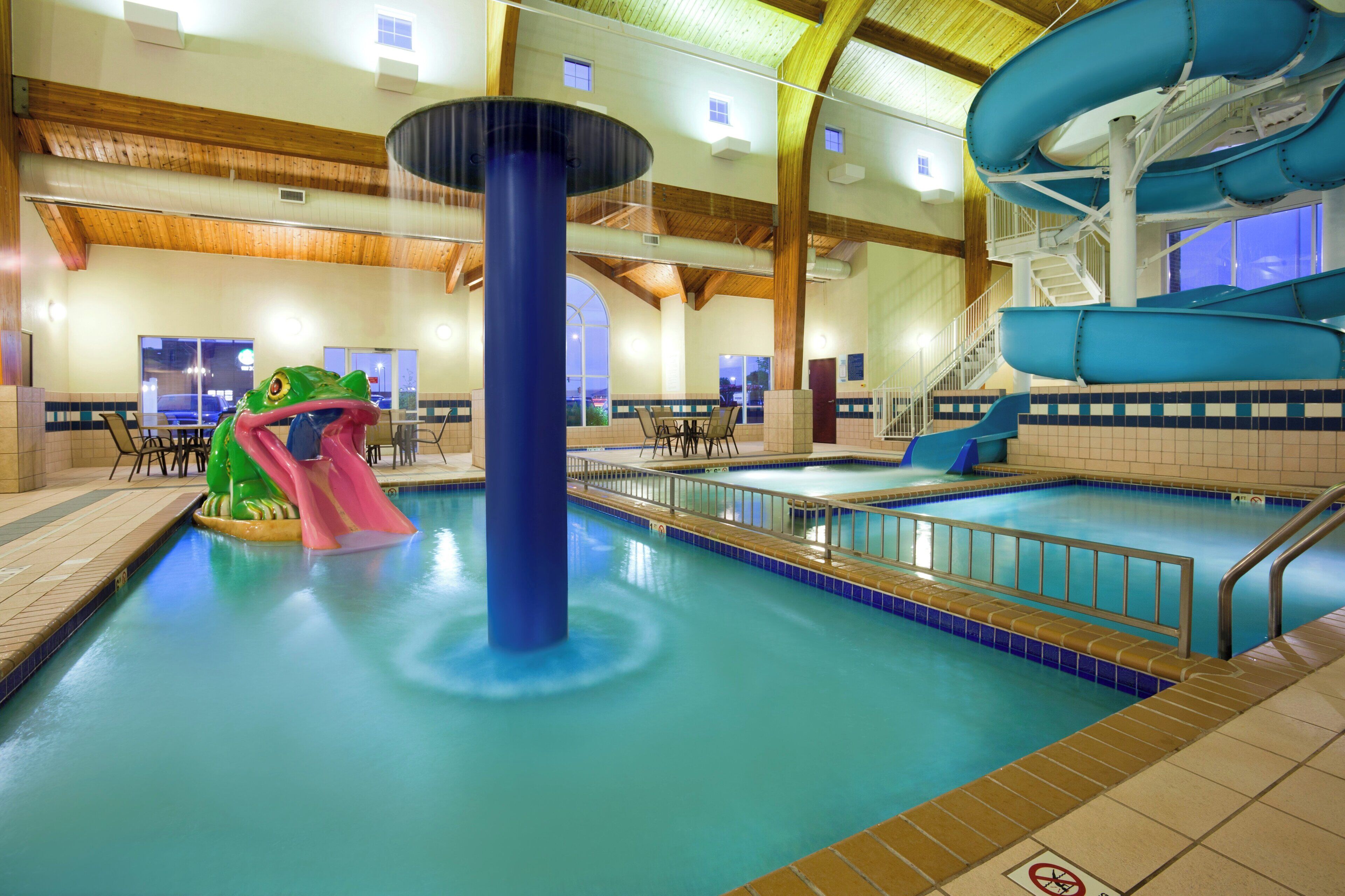 Une piscine intérieure avec un toboggan et un espace de jeux aquatiques.