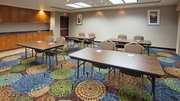 Uma sala de conferências com piso coberto por carpete, mesas de madeira e cadeiras.