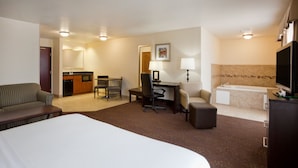 Ein Hotelzimmer mit einem großen Bett, einem Schreibtisch mit Stuhl, einer Couch, einem kleinen Tisch, einem Fernseher und einem Badezimmer mit Badewanne.