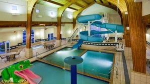 Una piscina interior amb tobogan, un tobogan aquàtic i una font d'aigua amb forma de granota.