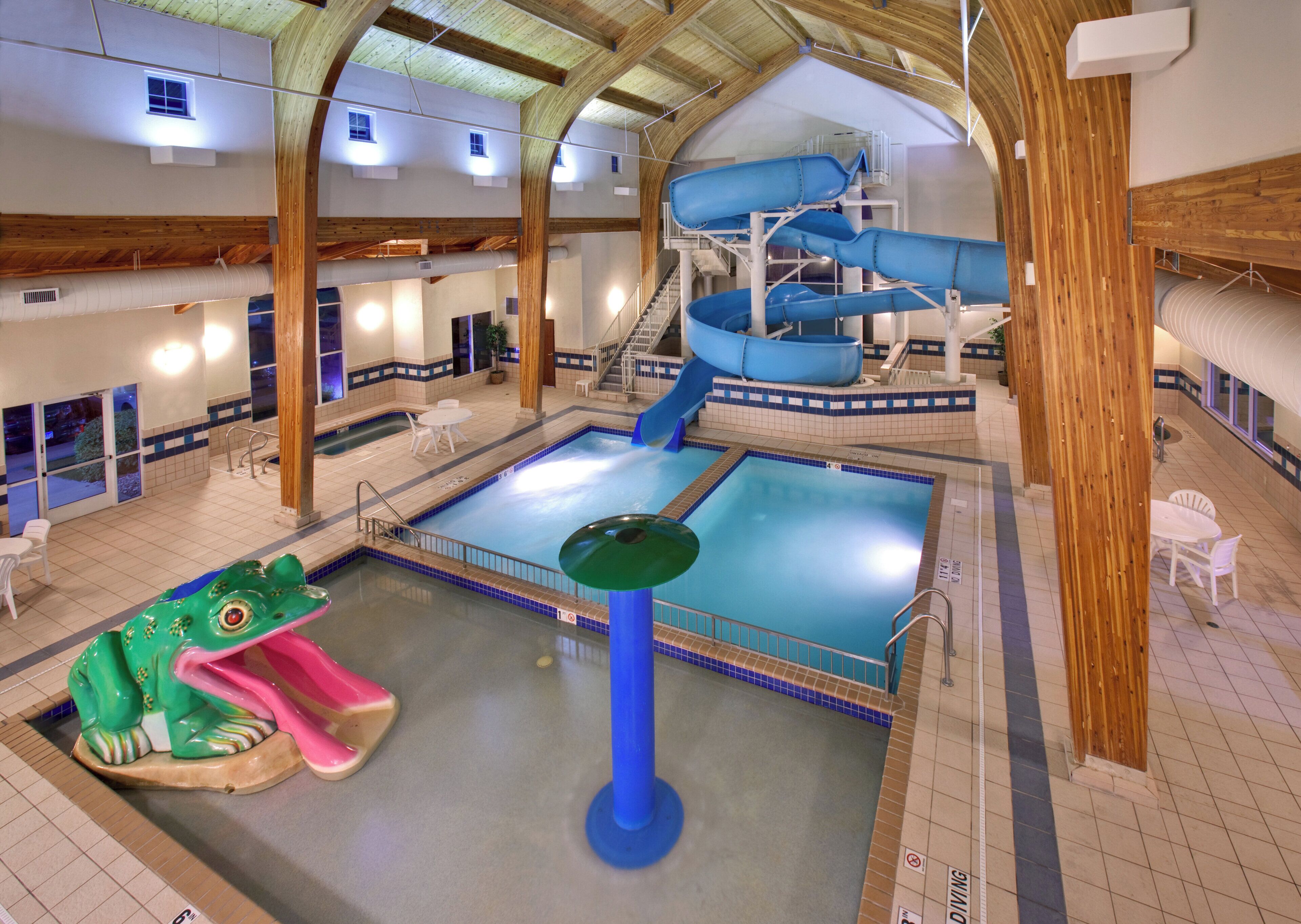 An indoor swimming pool with a slide, a diving board, and a water slide structure.