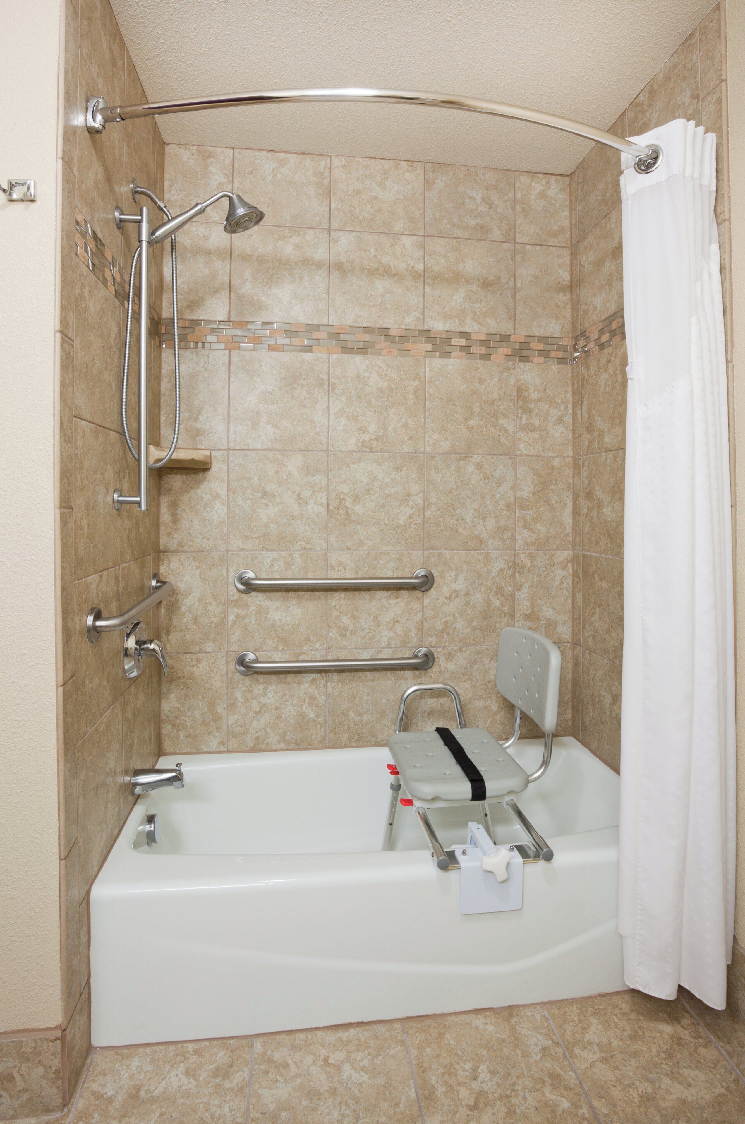 A bathroom with a walk-in shower, grab bars, a wheelchair-accessible bench, and a white bathtub.