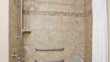 A bathroom with a walk-in shower, grab bars, a wheelchair-accessible bench, and a white bathtub.
