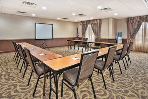 A conference room with a long table, chairs, a projector screen, and an American flag. - Holiday Inn Express Hotel & Suites Harrington-Dover area, DE by IHG (Harrington)
