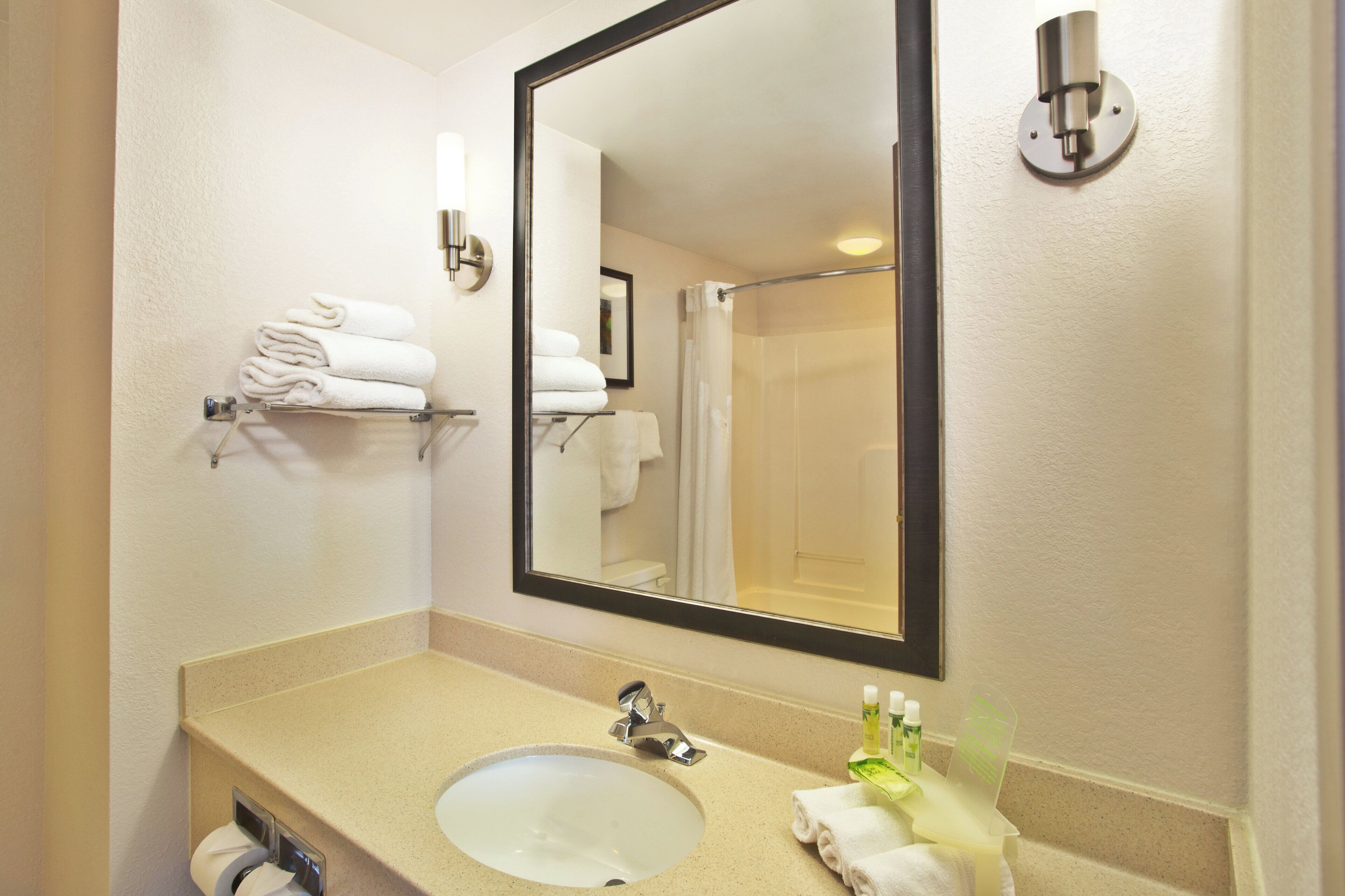 Une salle de bain équipée d’un lavabo, d’un miroir, d’un porte-serviettes et d’articles de toilette.