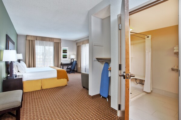 Ein Hotelzimmer mit Bett, Schreibtisch, Stuhl, Sofa, Dusche und Badezimmer.