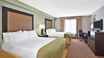Quarto de hotel com duas camas, uma escrivaninha, uma cadeira e uma televisão.