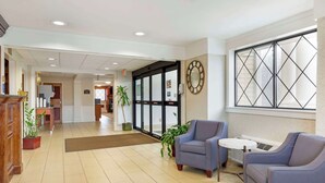 A hotel lobby with a reception desk, seating area, and a large window with a geometric pattern. - Best Western The Inn at Sharon/Foxboro (Sharon)