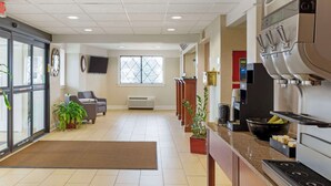A hotel lobby with a reception desk, seating area, and a kitchenette with a coffee machine. - Best Western The Inn at Sharon/Foxboro (Sharon)