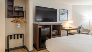A hotel room with a bed, a desk with a lamp, a TV, a microwave, a mini-fridge, a coat rack, and a coat hanging. - Best Western The Inn at Sharon/Foxboro (Sharon)