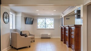 A spacious room with a large window, a comfortable chair, a flat-screen TV, and a wooden cabinet. - Best Western The Inn at Sharon/Foxboro (Sharon)