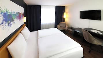 Ein Hotelzimmer mit einem großen Bett, einem Schreibtisch, einem Stuhl, einem Fernseher und einem Stadtbild an der Wand.