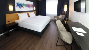 A hotel room with a large bed, a desk with a chair, a TV, and a painting on the wall. - greet Hotel Potsdam am Park Sanssouci (frisch renoviert) (Potsdam)