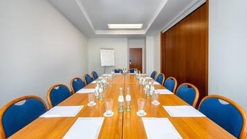 A conference room with a long wooden table, blue chairs, and a whiteboard.