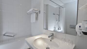 A modern bathroom with a white sink, a glass shower enclosure, and a towel rack.