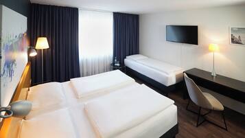 A hotel room with two beds, a desk, a chair, a TV, and a painting on the wall.
