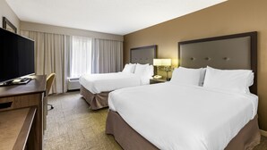 Una habitación de hotel con dos camas, un escritorio, una silla y un televisor.