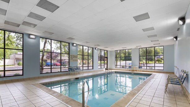 Una piscina interior con vistas despejadas al exterior, suelo de baldosas y un cartel que indica que no hay socorrista de servicio.