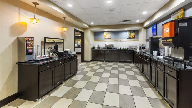 A commercial kitchen with checkered flooring, dark cabinetry, and various appliances.